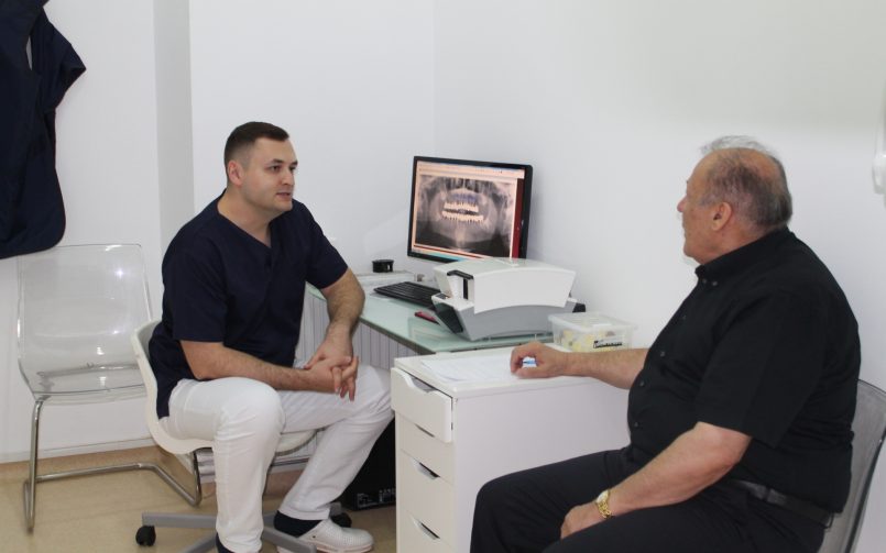 Dr. Ionuț leahu discutând cu un pacient după realizarea unei radiografii dentare