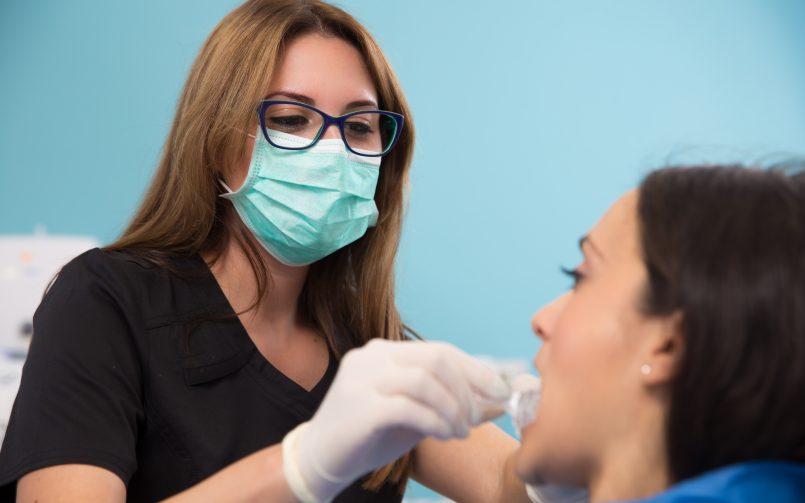 Medic stomatolog care examinează o pacientă cu dinte rupt