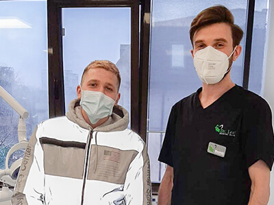 Medic stomatolog in dreapta, pacient in stanga in cabinetul de medicina dentara