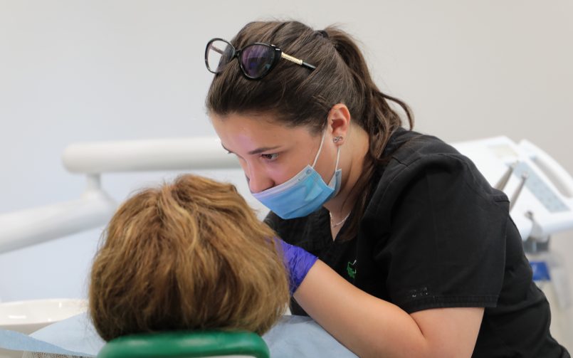 Medic dentist care examinează un pacient cu afte bucale