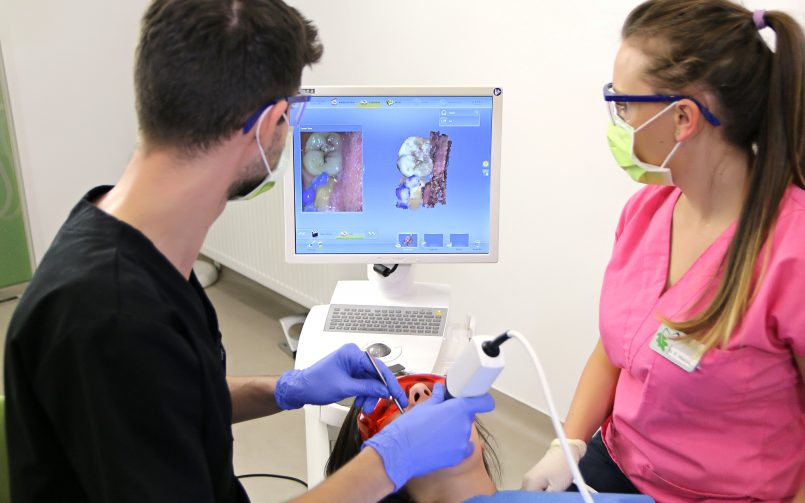 Medic si asistenta in timpul unei interventii stomatologice, cu monitor