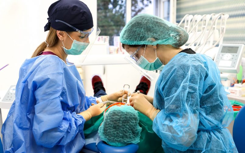 doctor chirurg in dreapta si asistenta in stanga in timpul inserarii implantului dentar