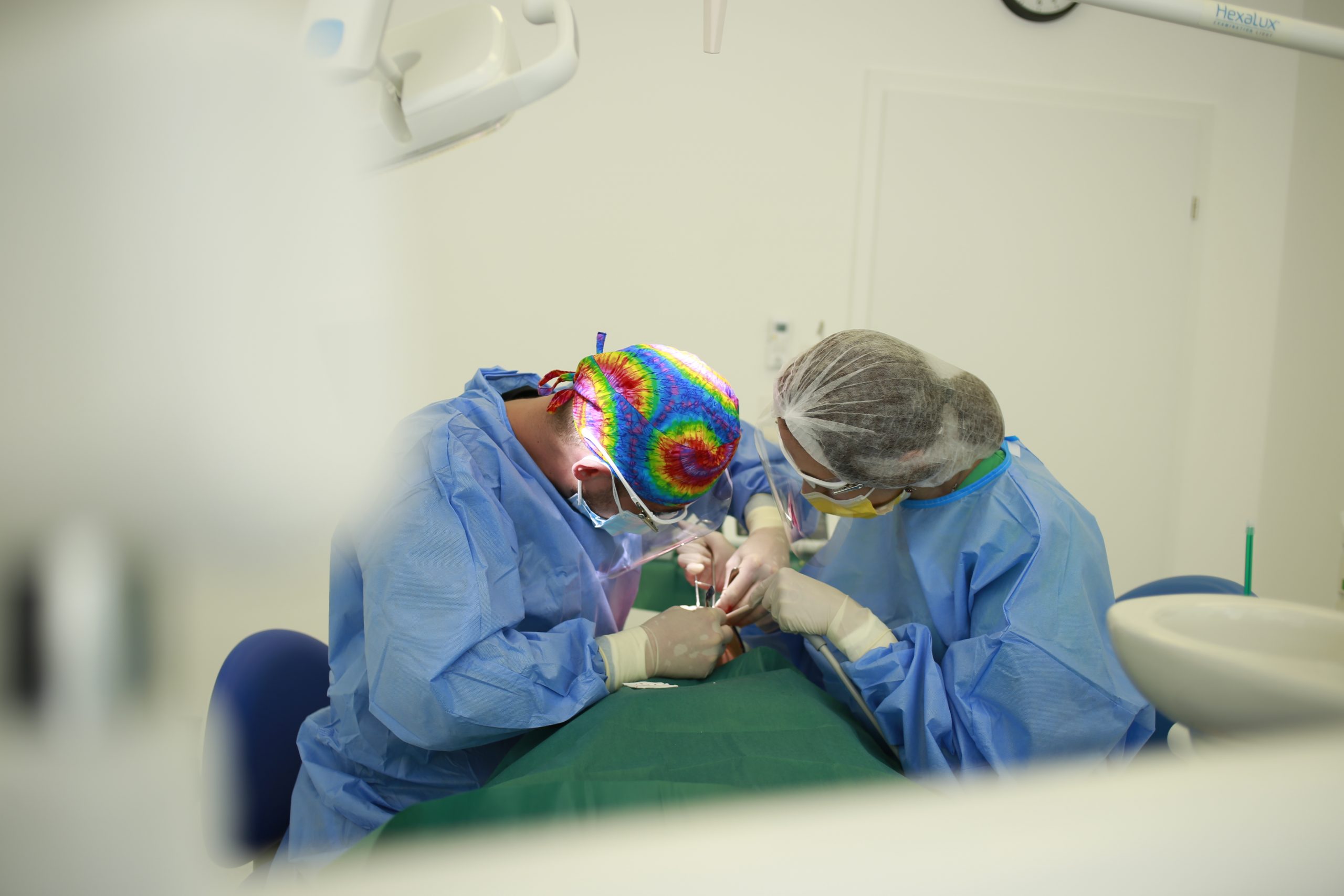 interventie chirurgicala cu implant dentar inserat de medic in stanga si asistent in dreapta 