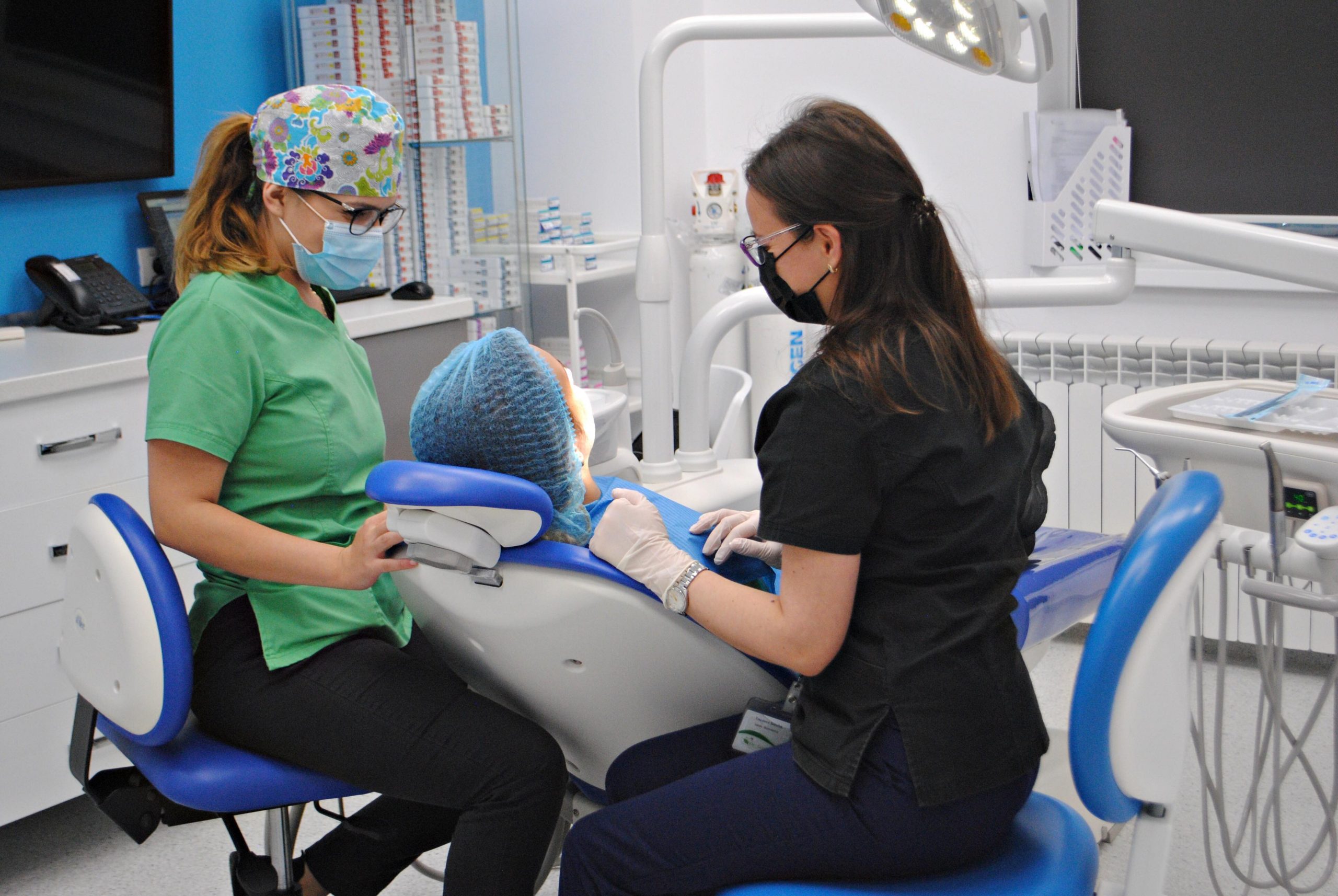 Dr. Satuha Teodora in dreapta scaunului stomatologic si asistent imedical in stanga in timpul interventiei 