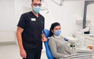 Medic stomatolog in stanga, pacient in dreapta in cabinetul de medicina dentara