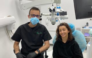 Medic stomatolog in stanga, pacient in dreapta in cabinetul de medicina dentara