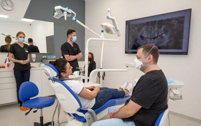 Medici stomatologi in cabinetul de medicina dentara, pacient pe scaunul stomatologic