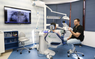 radiografie dentara in stanga, pacient pe scaun, medic stomatolog in dreapta